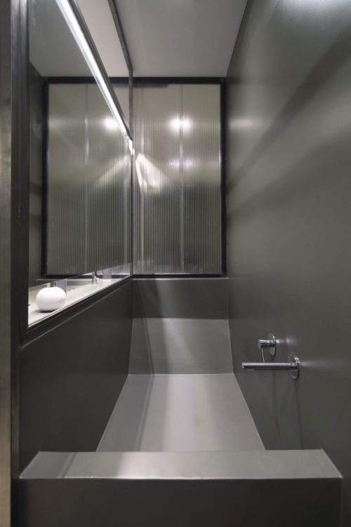 Verborgen ligbad in een stoere badkamer