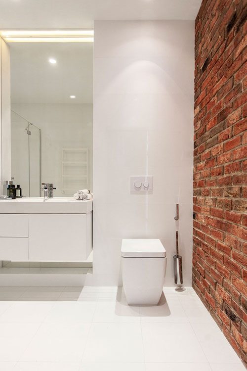 Witte badkamer met bakstenen muur
